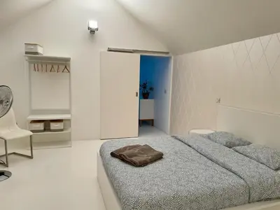 a white bedroom with a bed and a chair at Luxurious villa during tomorrowland in Hemiksem