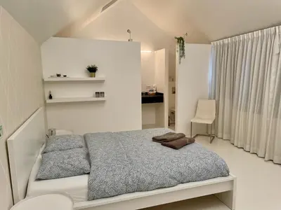 a white bedroom with a bed and a chair at Luxurious villa during tomorrowland in Hemiksem