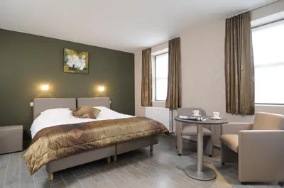 a bedroom with a bed and a table and chairs at Gastenhof Ter Lombeek in Onze-Lieve-Vrouw-Lombeek