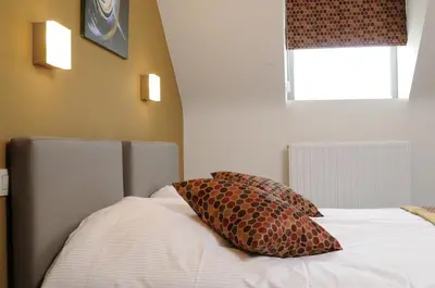 a bed with two pillows on it with a window at Gastenhof Ter Lombeek in Onze-Lieve-Vrouw-Lombeek