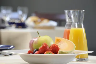 a bowl of fruit on a table with a glass of orange juice at Gastenhof Ter Lombeek in Onze-Lieve-Vrouw-Lombeek