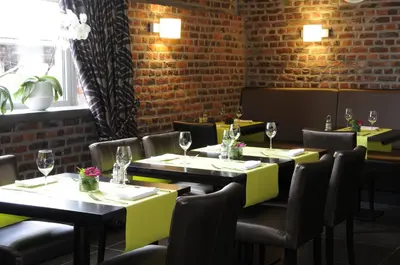 a restaurant with tables and chairs and a brick wall at Gastenhof Ter Lombeek in Onze-Lieve-Vrouw-Lombeek