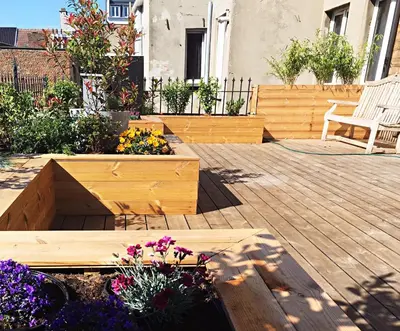 a patio with a wooden deck with flowers and a bench at Kloosterloft in Antwerp