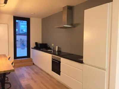 a kitchen with white cabinets and a black counter top at Kloosterloft in Antwerp