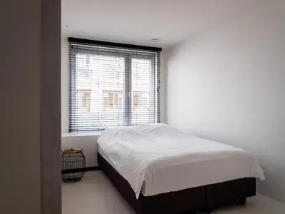 a white bedroom with a bed and a window at Maison N in Ghent