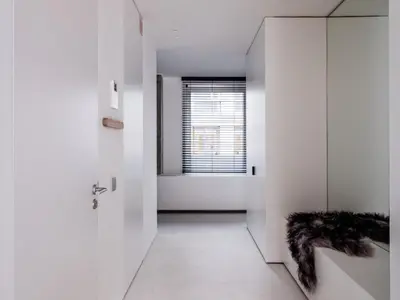 a hallway with white walls and a door with a window at Maison N in Ghent