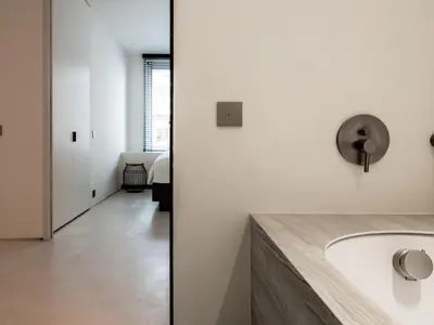 two views of a bathroom with a sink and a hallway at Maison N in Ghent