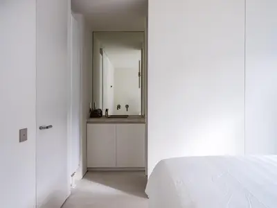 a white bedroom with a mirror and a bed at Maison N in Ghent