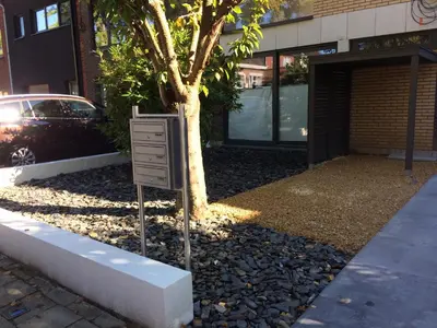 a sign next to a tree in front of a building at Appartement met groot terras in Mortsel