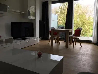 a living room with a television and a table and chairs at Appartement met groot terras in Mortsel