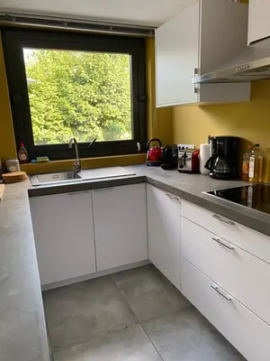 a kitchen with white cabinets and a window at Appartement met groot terras in Mortsel