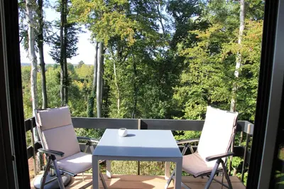 a table and chairs on a balcony with a view of trees at Green Hill Apartment Overijse in Overijse
