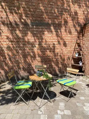 two chairs and a table in front of a brick wall at B & B Simme Zimme in Brasschaat