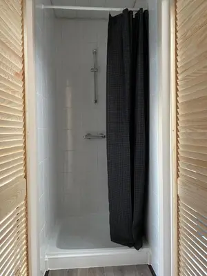 a shower stall in a bathroom with a shower curtain at B & B Simme Zimme in Brasschaat