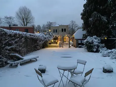 a yard covered in snow with chairs and a bench at B & B Simme Zimme in Brasschaat