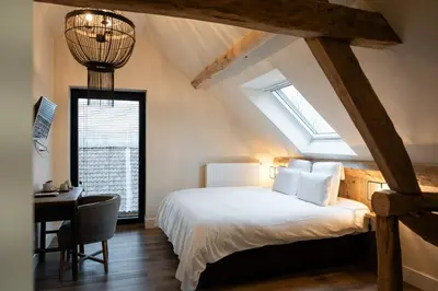a bedroom with a bed and a desk and a window at B&B Langeveldemolen in Merchtem