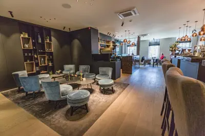 a restaurant with chairs and tables and a bar at Hotel De Jachthoorn in Hoogstraten