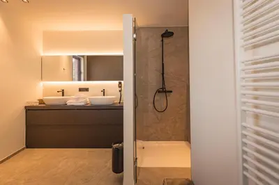 a bathroom with two sinks and a shower at Hotel De Jachthoorn in Hoogstraten
