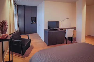 a room with a desk with a television and a chair at Hotel De Jachthoorn in Hoogstraten