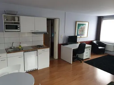 a kitchen with white cabinets and a desk in a room at JFK Hotel Zelzate - Gent in Zelzate