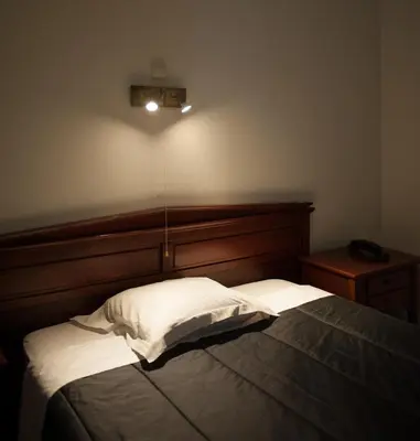 a bedroom with a bed with a wooden headboard at JFK Hotel Zelzate - Gent in Zelzate