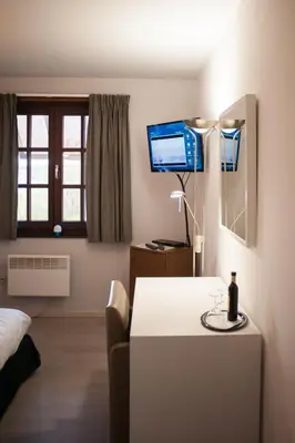 a room with a bed and a table and a television at JFK Hotel Zelzate - Gent in Zelzate