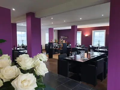 a dining room with tables and white roses at JFK Hotel Zelzate - Gent in Zelzate