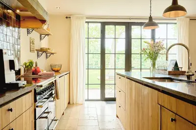 a kitchen with wooden cabinets and a large window at Muntershof in Velzeke-Ruddershove