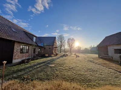 an old farm with the sun setting in the background at Muntershof in Velzeke-Ruddershove