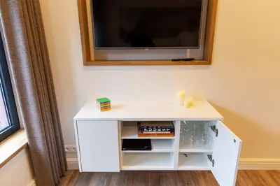 a white cabinet with a tv on a wall at B&B Steendam 66 in Ghent