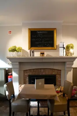 a dining room with a table and a fireplace at Logies De blauwe regen in Beveren