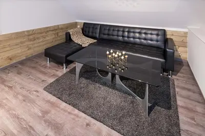 a living room with a black leather couch and a table at Logies De blauwe regen in Beveren