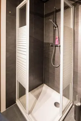 a shower with a glass enclosure in a bathroom at Logies De blauwe regen in Beveren