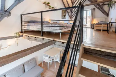 a loft bedroom with a bed and a table and chairs at Tempel Cathedral Lodge in the Heart of Antwerp in Antwerp