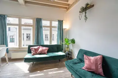a living room with a green couch and pink pillows at Tempel Cathedral Lodge in the Heart of Antwerp in Antwerp
