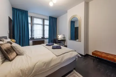 a bedroom with a large bed with blue curtains at Fish Market Apartments in Brussels