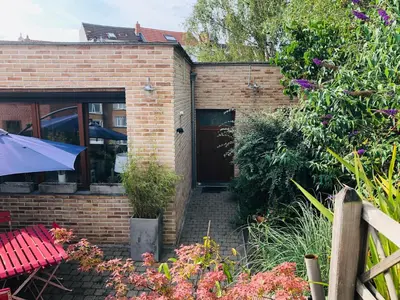 a brick house with a door in a garden at Apartment Easyway to sleep in Brussels