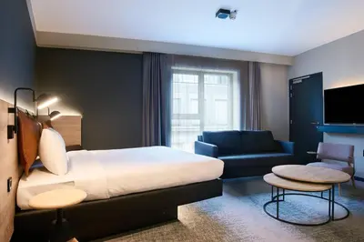 a hotel room with a bed and a couch at Moxy Brussels City Center in Brussels