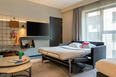 a hotel room with a bed and a tv at Moxy Brussels City Center in Brussels