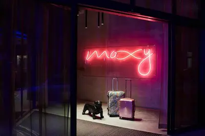 a neon sign in a store window with luggage at Moxy Brussels City Center in Brussels