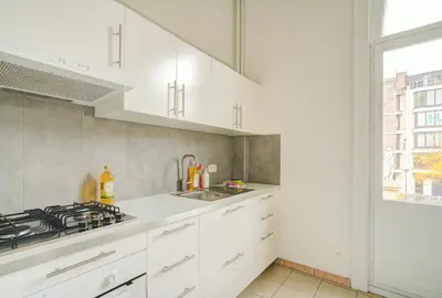 a kitchen with white cabinets and a sink and a window at The National Lodge in Antwerp
