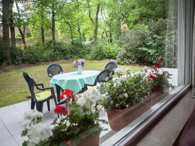 a table and chairs on a porch with flowers at Westmalle Forest Garden Home in Zoersel