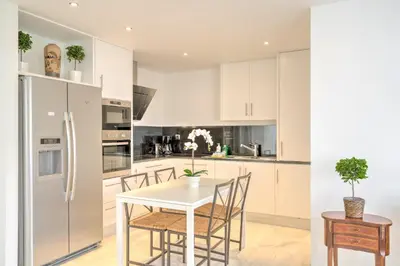 a kitchen with white cabinets and a white table and chairs at The Antwerp Marble Lodge in Antwerp