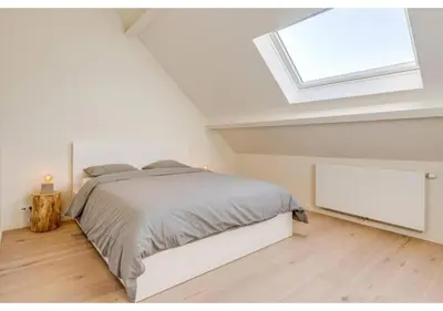 a white bedroom with a bed and a skylight at The Heart of Leuven in Leuven