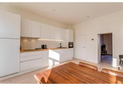 a kitchen with white cabinets and a wooden table at The Heart of Leuven in Leuven