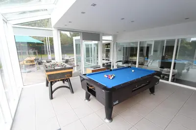 a pool table in a room with glass walls at NUVOLA VILLA in Zottegem