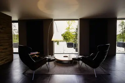 a living room with chairs and a table and a large window at Loft Aan Het Water in Grobbendonk
