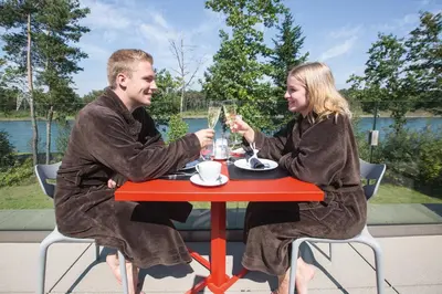 a man and woman sitting at a red table with drinks at Loft Aan Het Water in Grobbendonk