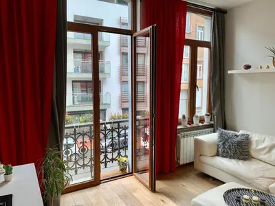 a living room with a large window with red curtains at Grand Appartement Jourdan EU in Brussels