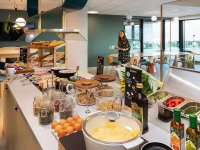 a woman standing in a kitchen with a table with food at Adagio access Brussels Delta in Brussels